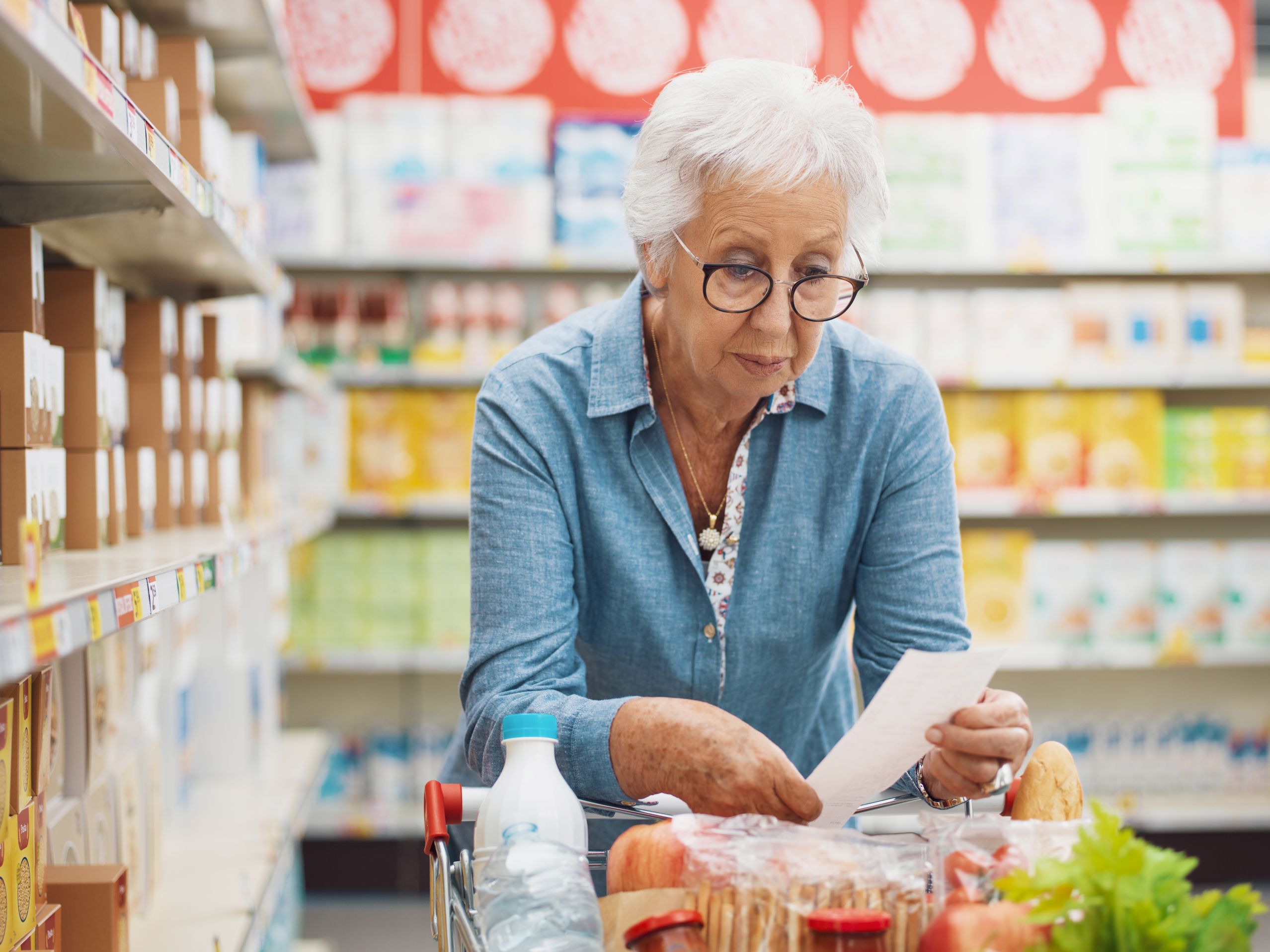 Senior woman reviews her grocery list at the supermarket.